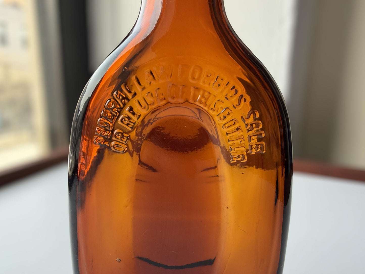 Vintage amber flat scotch bottle 7 inches tall with ornate embossed front design, hand-recovered from NYC mid-century dumping grounds – Brooklyn Sea Glass