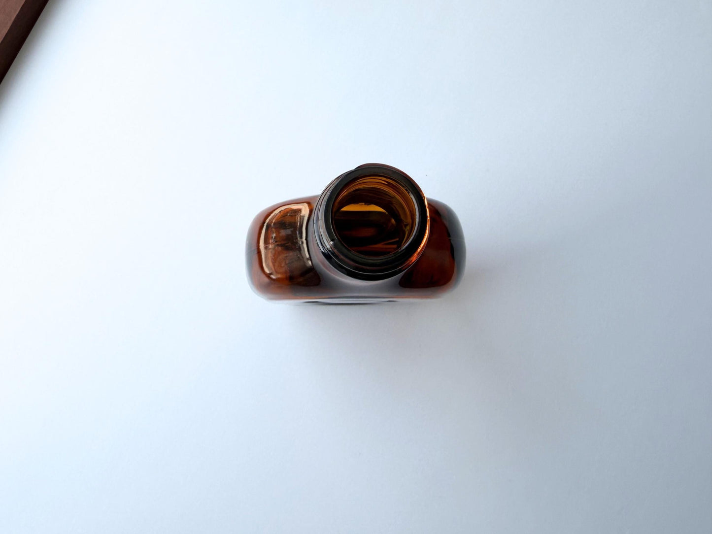 Vintage amber flat scotch bottle, 7 inches tall with ornate embossed front design, hand-recovered from NYC mid-century dumping grounds — authentic mid-century spirits bottle