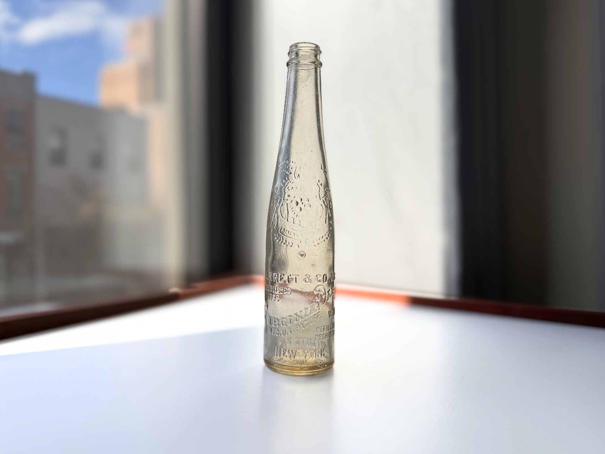 Vintage Garrett and Co Virginia Dare clear glass wine bottle 8.75 inches tall with full-body embossed crest and pre-Prohibition text - hand-recovered from NYC dumping grounds