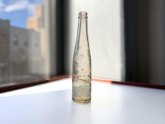 Vintage Garrett and Co Virginia Dare clear glass wine bottle 8.75 inches tall with full-body embossed crest and pre-Prohibition text - hand-recovered from NYC dumping grounds