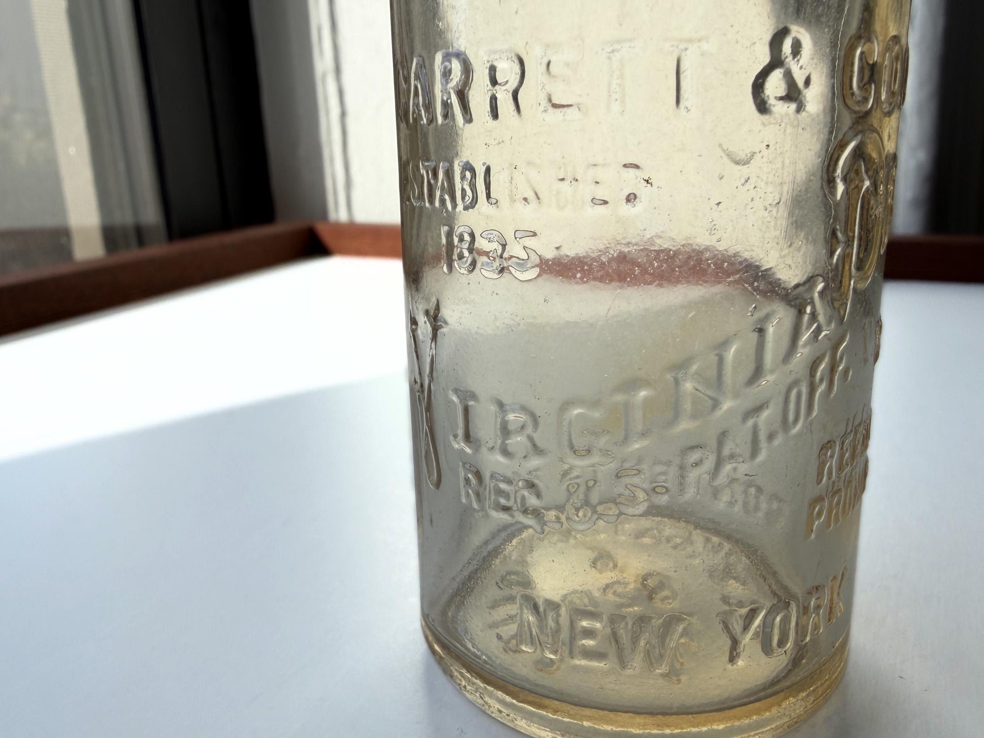 Vintage Garrett and Co Virginia Dare clear glass wine bottle 8.75 inches tall with full-body embossed crest and pre-Prohibition text - hand-recovered from NYC dumping grounds