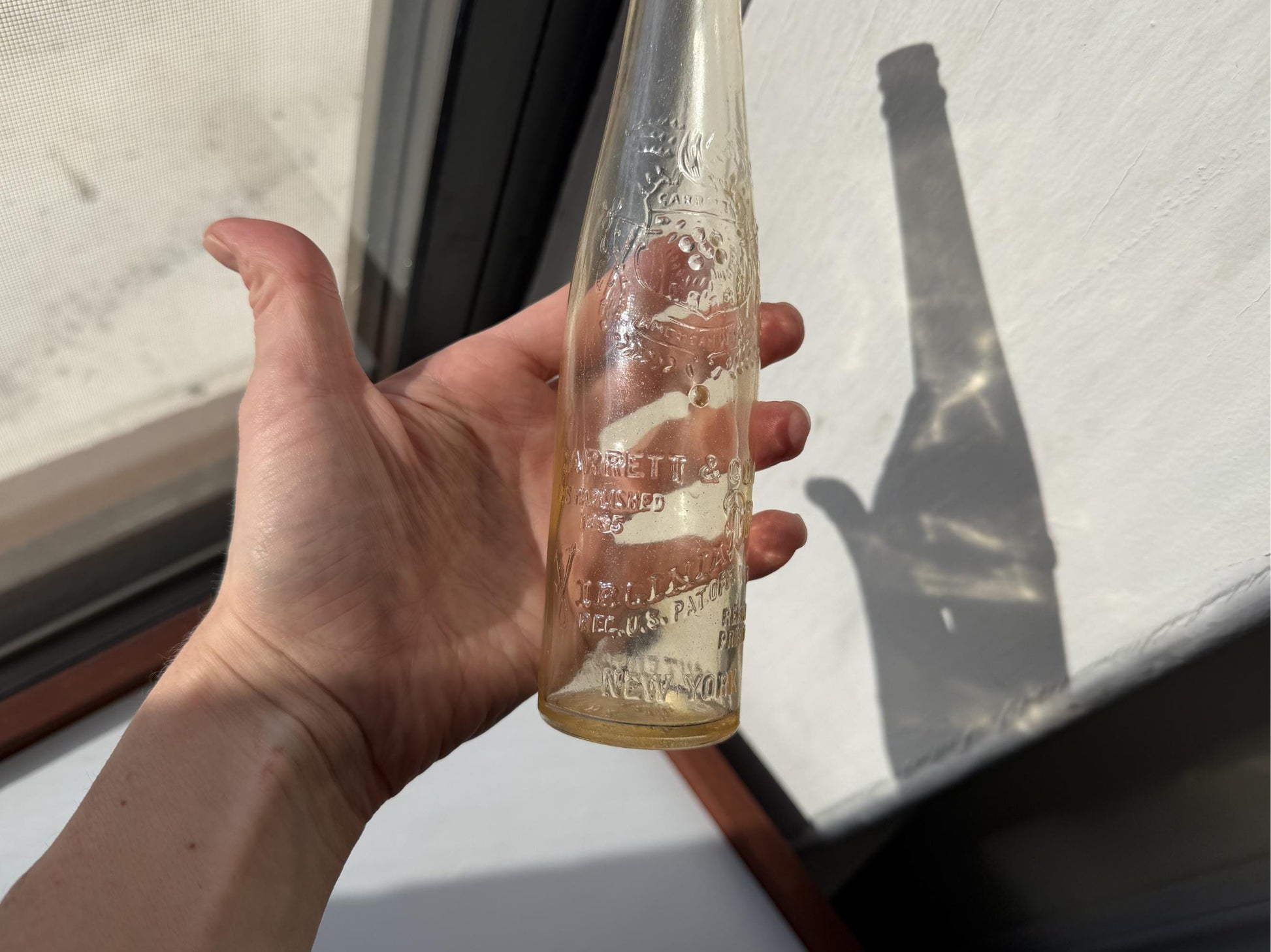 Vintage Garrett and Co Virginia Dare clear glass wine bottle 8.75 inches tall with full-body embossed crest and pre-Prohibition text - hand-recovered from NYC dumping grounds