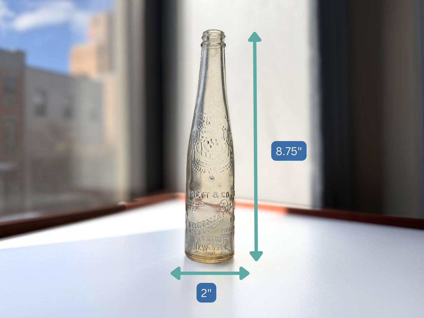 Vintage Garrett and Co Virginia Dare clear glass wine bottle 8.75 inches tall with full-body embossed crest and pre-Prohibition text - hand-recovered from NYC dumping grounds