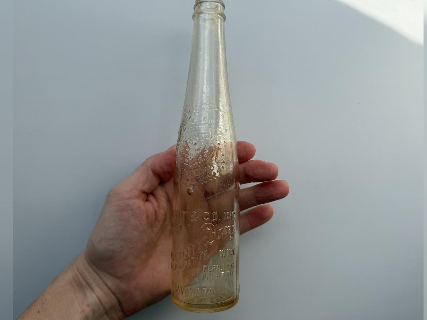 Vintage Garrett and Co Virginia Dare clear glass wine bottle 8.75 inches tall with full-body embossed crest and pre-Prohibition text - hand-recovered from NYC dumping grounds