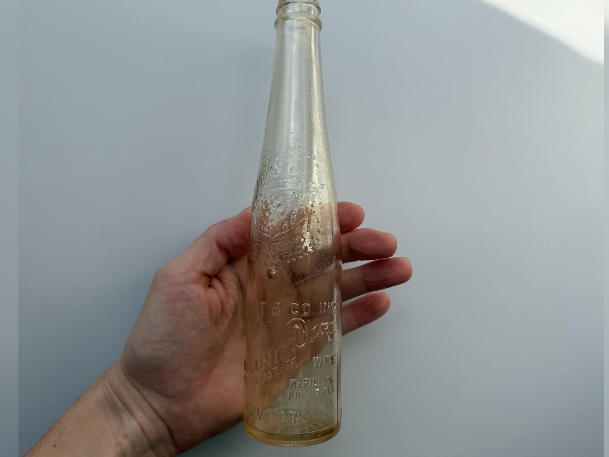 Vintage Garrett and Co Virginia Dare clear glass wine bottle 8.75 inches tall with full-body embossed crest and pre-Prohibition text - hand-recovered from NYC dumping grounds