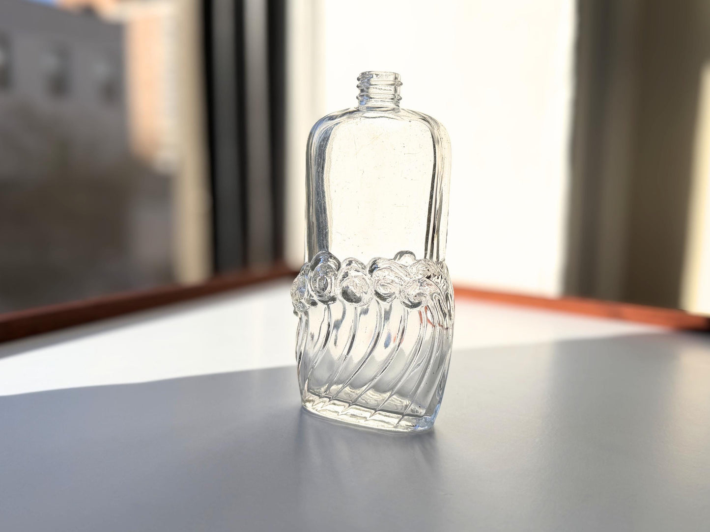 Vintage glass waves textured bottle with distinctive wavy pattern throughout. Clear glass with light patina. Perfect for vintage glass collectors and pattern enthusiasts.
