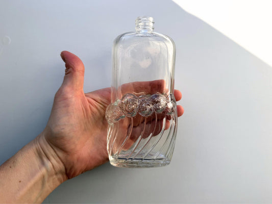 Vintage glass waves textured bottle with distinctive wavy pattern throughout. Clear glass with light patina. Perfect for vintage glass collectors and pattern enthusiasts.