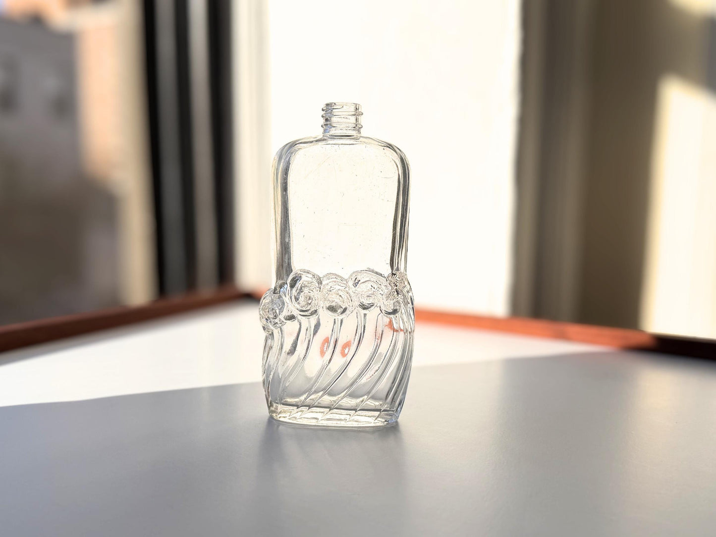 Vintage glass waves textured bottle with distinctive wavy pattern throughout. Clear glass with light patina. Perfect for vintage glass collectors and pattern enthusiasts.