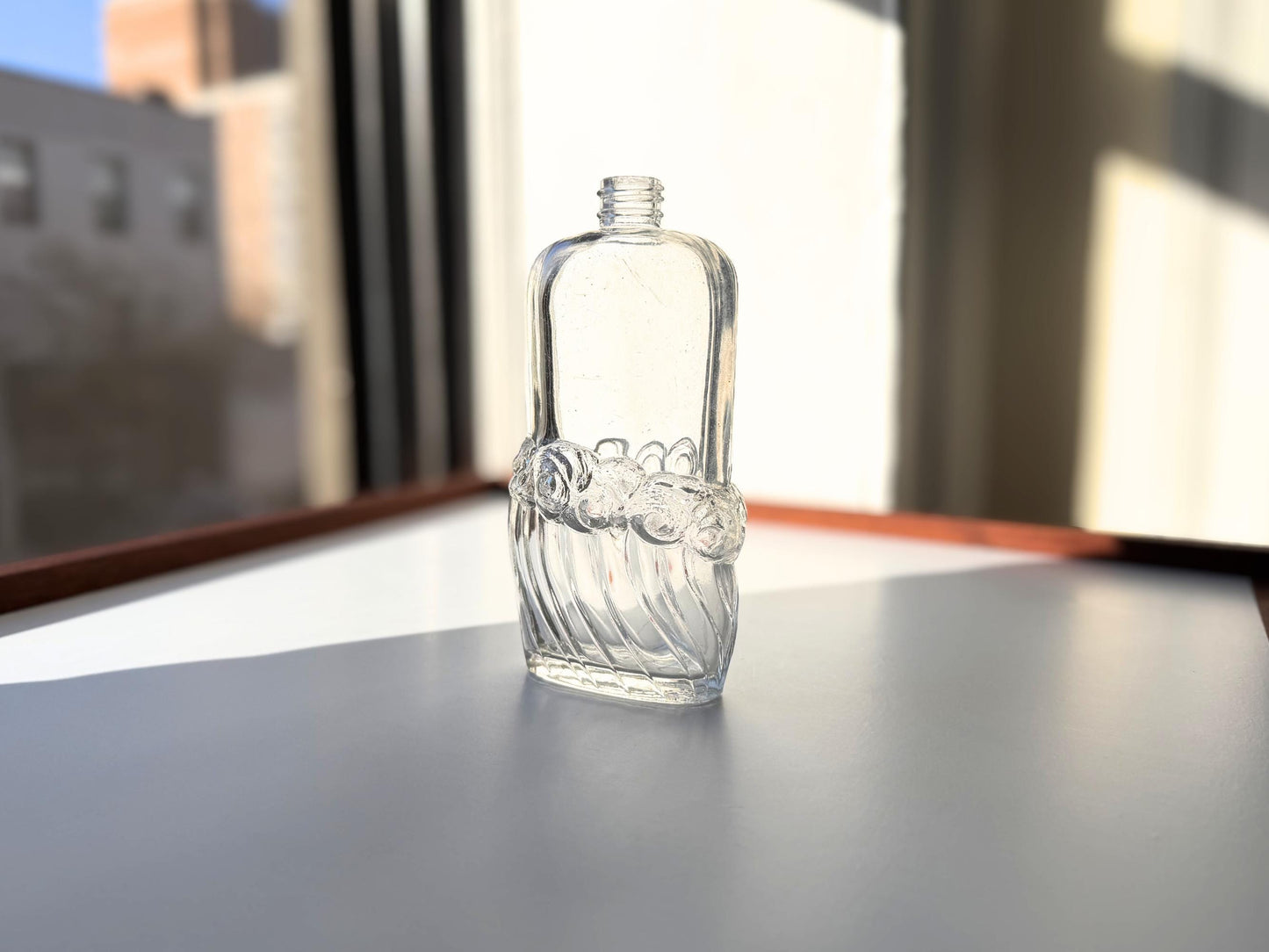Vintage glass waves textured bottle with distinctive wavy pattern throughout. Clear glass with light patina. Perfect for vintage glass collectors and pattern enthusiasts.