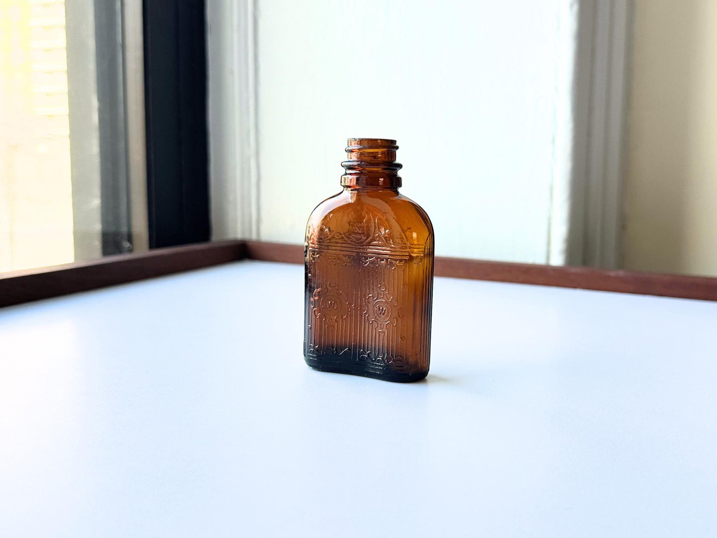 Vintage Hiram Walker small amber bottle with embossed "W" logo on bottom. Perfect for spirits collectors, bar displays, and vintage amber glass enthusiasts. Good condition warm amber glass bottle with minor nicks showing authentic vintage w