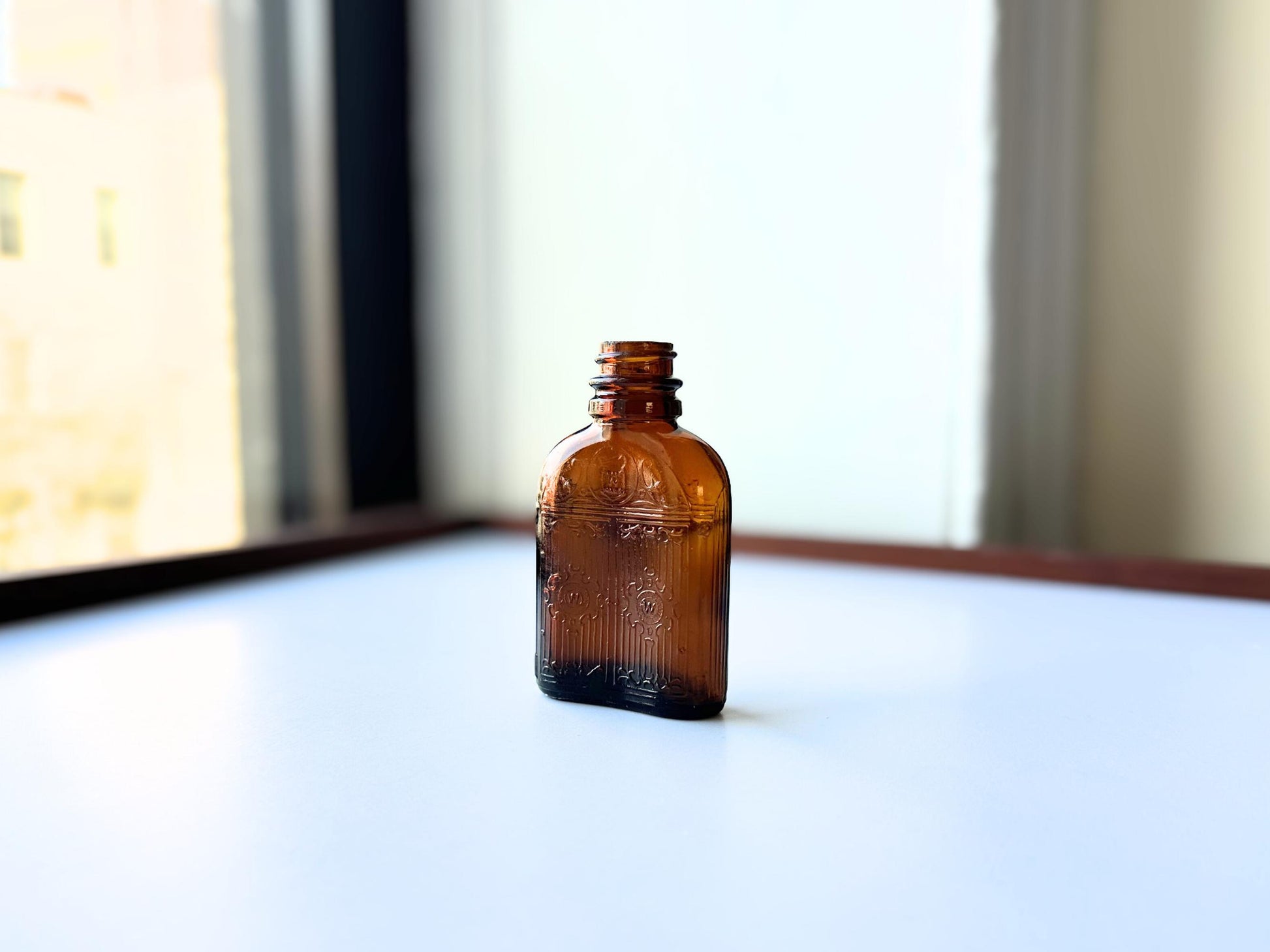 Vintage Hiram Walker small amber bottle with embossed "W" logo on bottom. Perfect for spirits collectors, bar displays, and vintage amber glass enthusiasts. Good condition warm amber glass bottle with minor nicks showing authentic vintage w