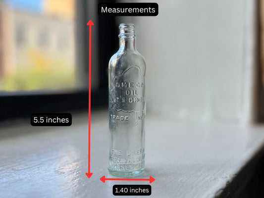 Vintage glass bottle with etched text OMEGA OIL IT'S GREAT TRADE MARK THE OMEGA CHEMICAL COMPANY JERSEY CITY. Clear, slightly frosted glass with a tapered neck and rounded base. Measurements: 5.5 inches tall and 1.40 inches wide.