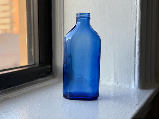 Side profile of vintage cobalt blue Phillips Milk of Magnesia bottle showcasing its rich color and elegant design – Brooklyn Sea Glass
