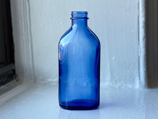 Back view of vintage cobalt blue Phillips Milk of Magnesia bottle highlighting its squared yet rounded design – Brooklyn Sea Glass