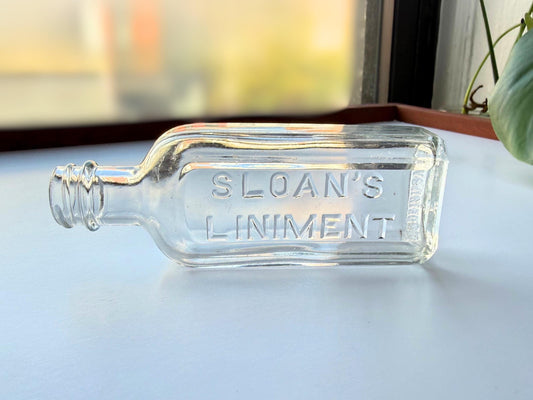 Authentic vintage Sloan's Liniment medicine bottle from 1940s-early 1950s in clear glass with embossed lettering and Made in USA base marking, perfect for apothecary collectors and vintage pharmacy displays.