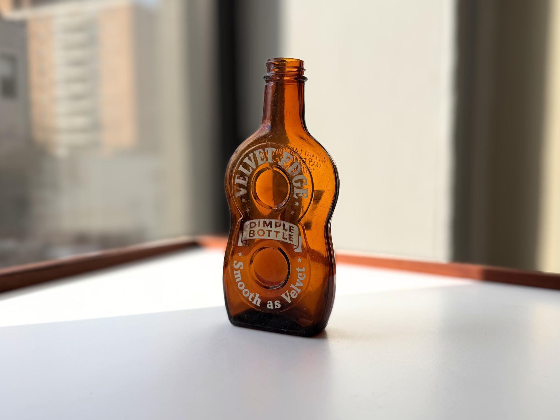 Vintage Velvet Edge amber dimple bottle 7 inches tall dated 1952 with figure-8 silhouette and Federal Law embossing - hand-recovered from NYC mid-century dumping grounds