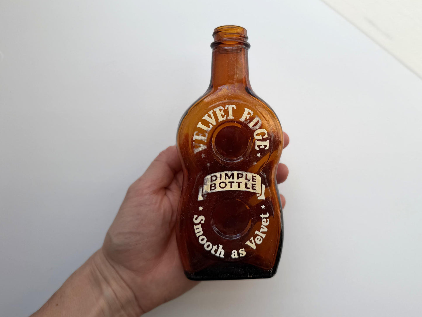 Vintage Velvet Edge amber dimple bottle 7 inches tall dated 1952 with figure-8 silhouette and Federal Law embossing - hand-recovered from NYC mid-century dumping grounds