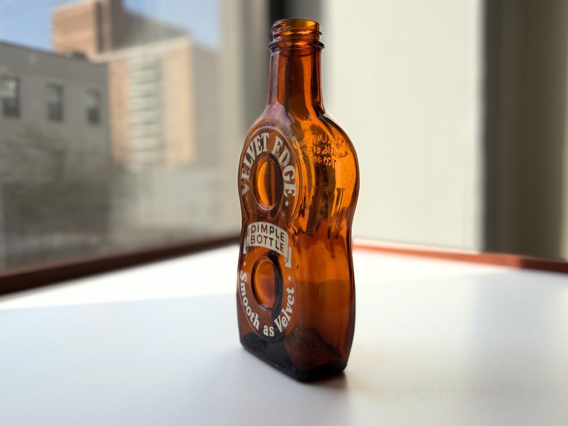 Vintage Velvet Edge amber dimple bottle 7 inches tall dated 1952 with figure-8 silhouette and Federal Law embossing - hand-recovered from NYC mid-century dumping grounds