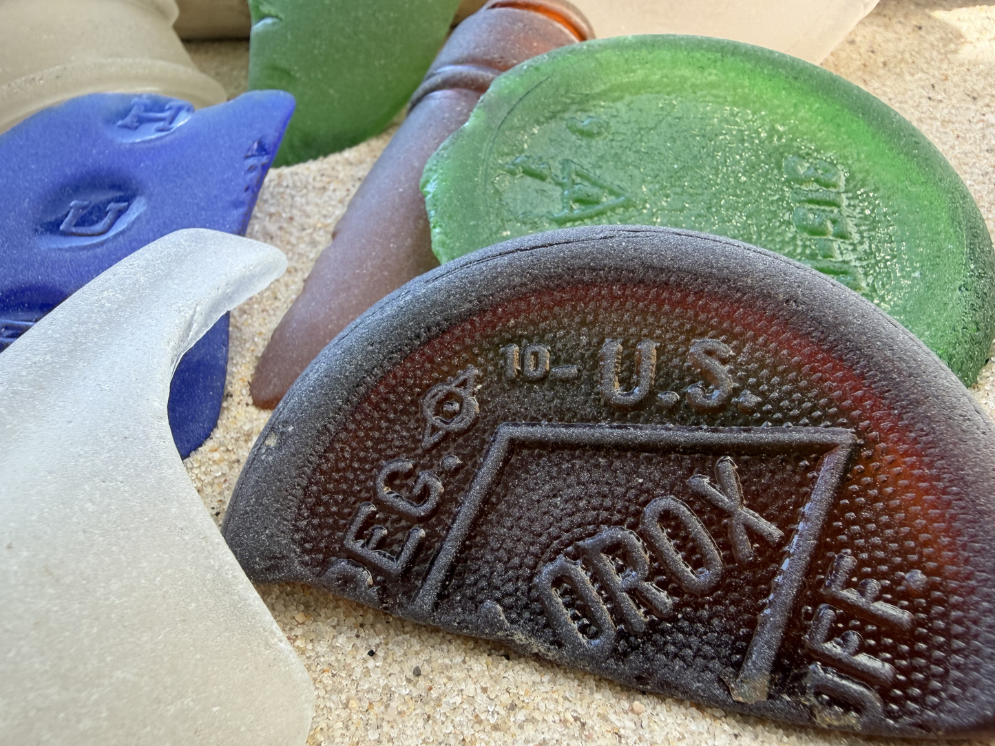 Close-up of XL sea glass showing antique embossed OROX marking, genuine NYC archaeological beach glass piece