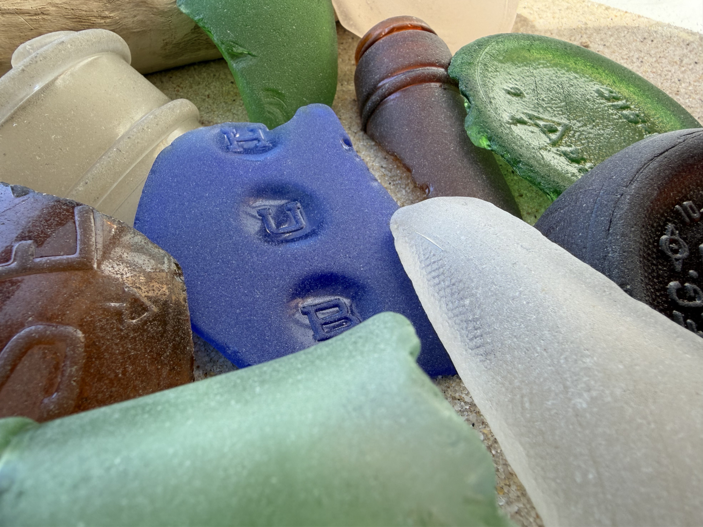 Macro detail of extra large sea glass showing vintage embossed markings, cobalt blue and green authentic NYC pieces