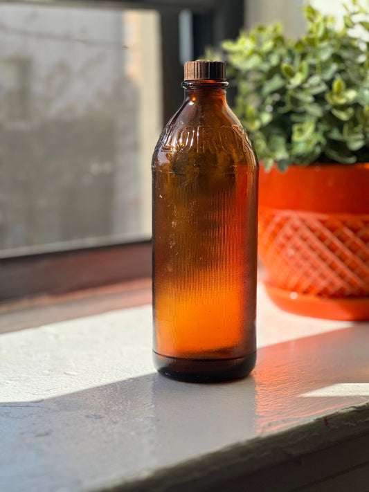 Clorox 1952 bottle side view showing warm amber glass and embossed branding, honest vintage patina