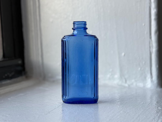 Cobalt blue medicine bottle close-up showing rectangular shape and fluted edges