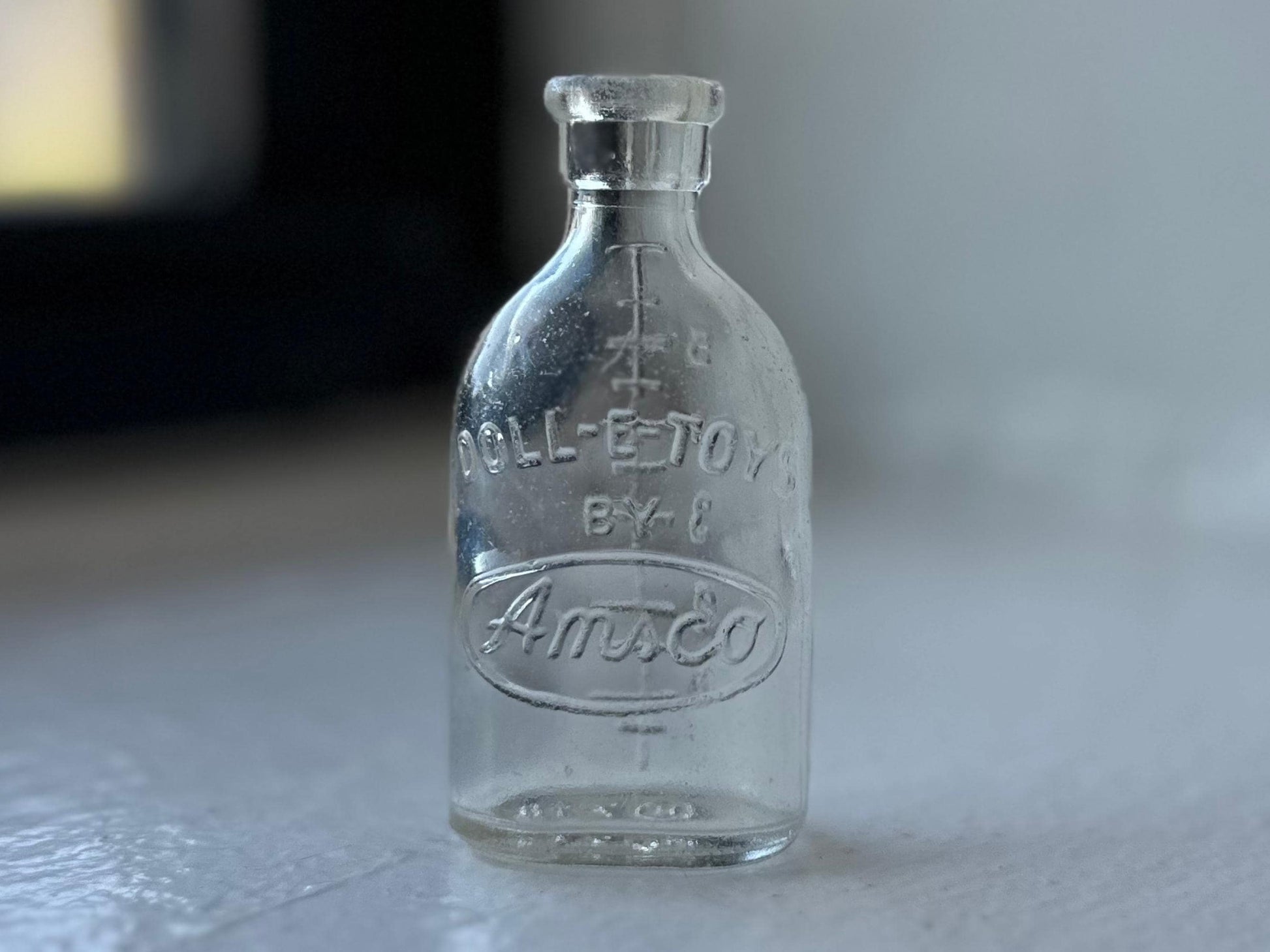 Doll-E-Toys Amsco miniature glass baby bottle full view, etched branding and graduated markings