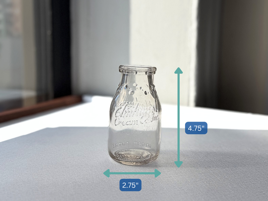 Close-up of ELMHURST CREAM CO INC front embossing on clear glass half-pint milk bottle, crisp and legible