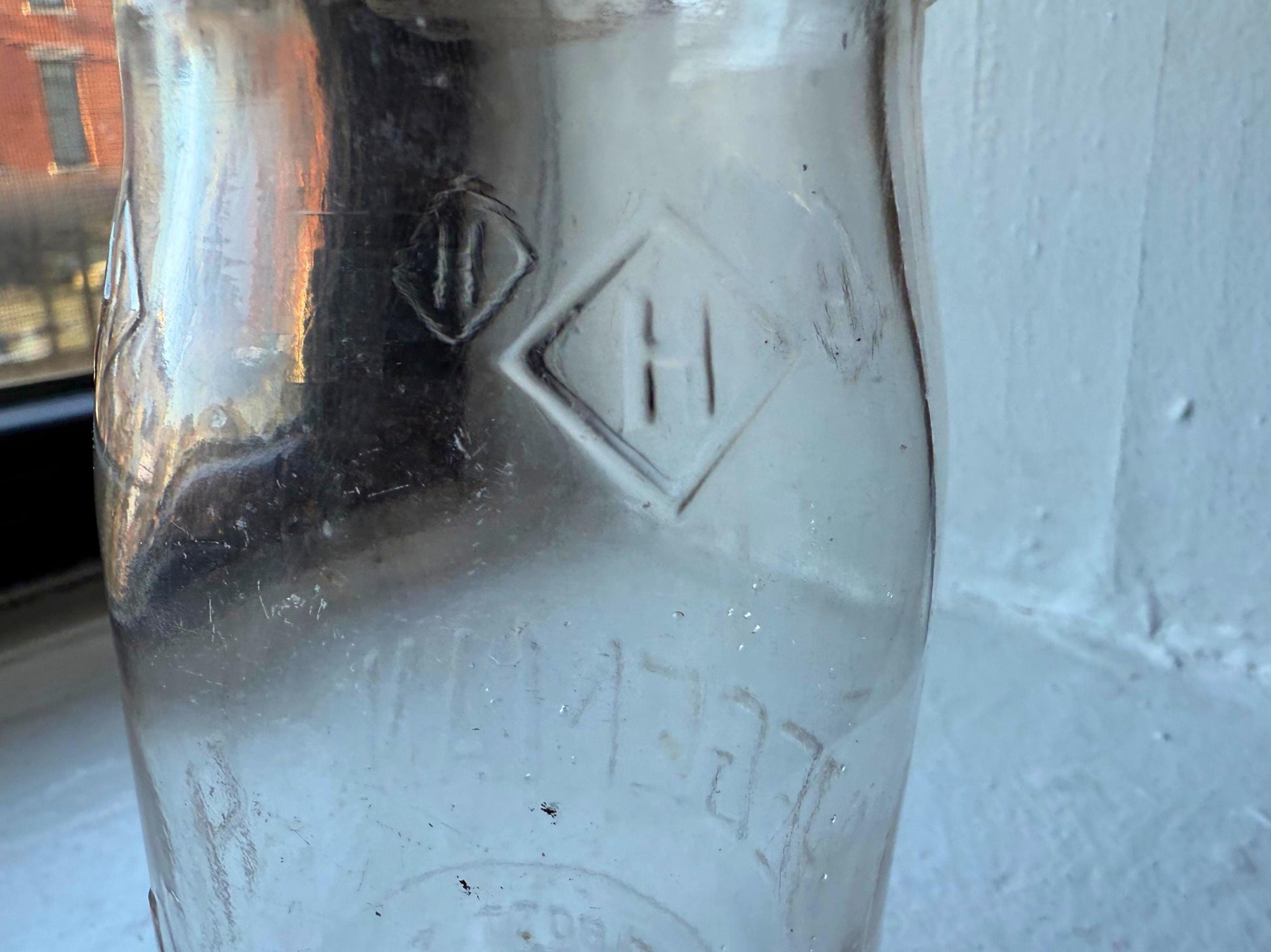 Hegeman diamond H logo embossing close-up on 1951 Queens NY clear glass milk bottle