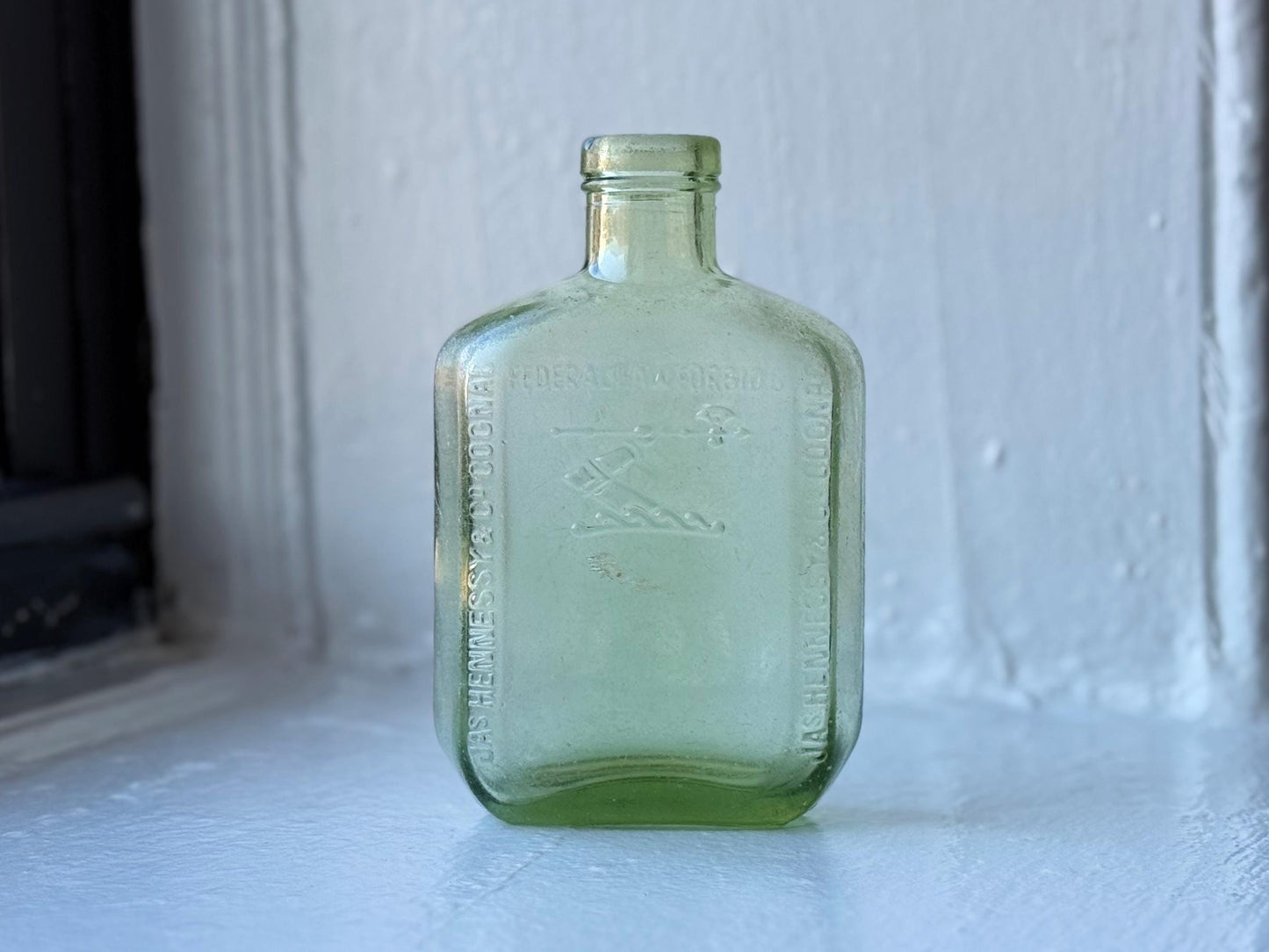Hennessy 1938 apple green glass cognac bottle full front view showing arm-and-axe crest embossing