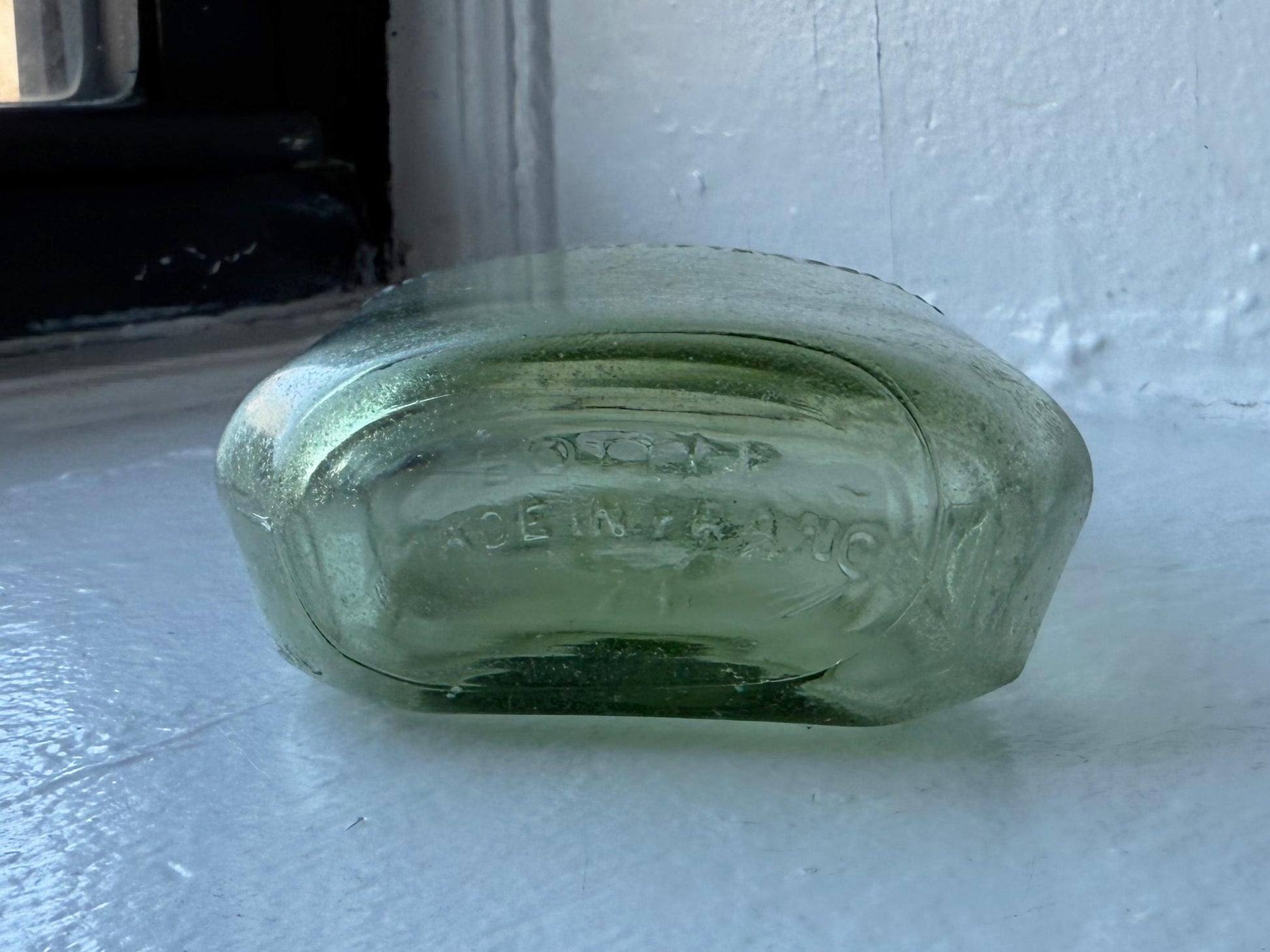 Hennessy arm-and-axe crest embossing close-up on apple green glass, Federal Law era cognac bottle