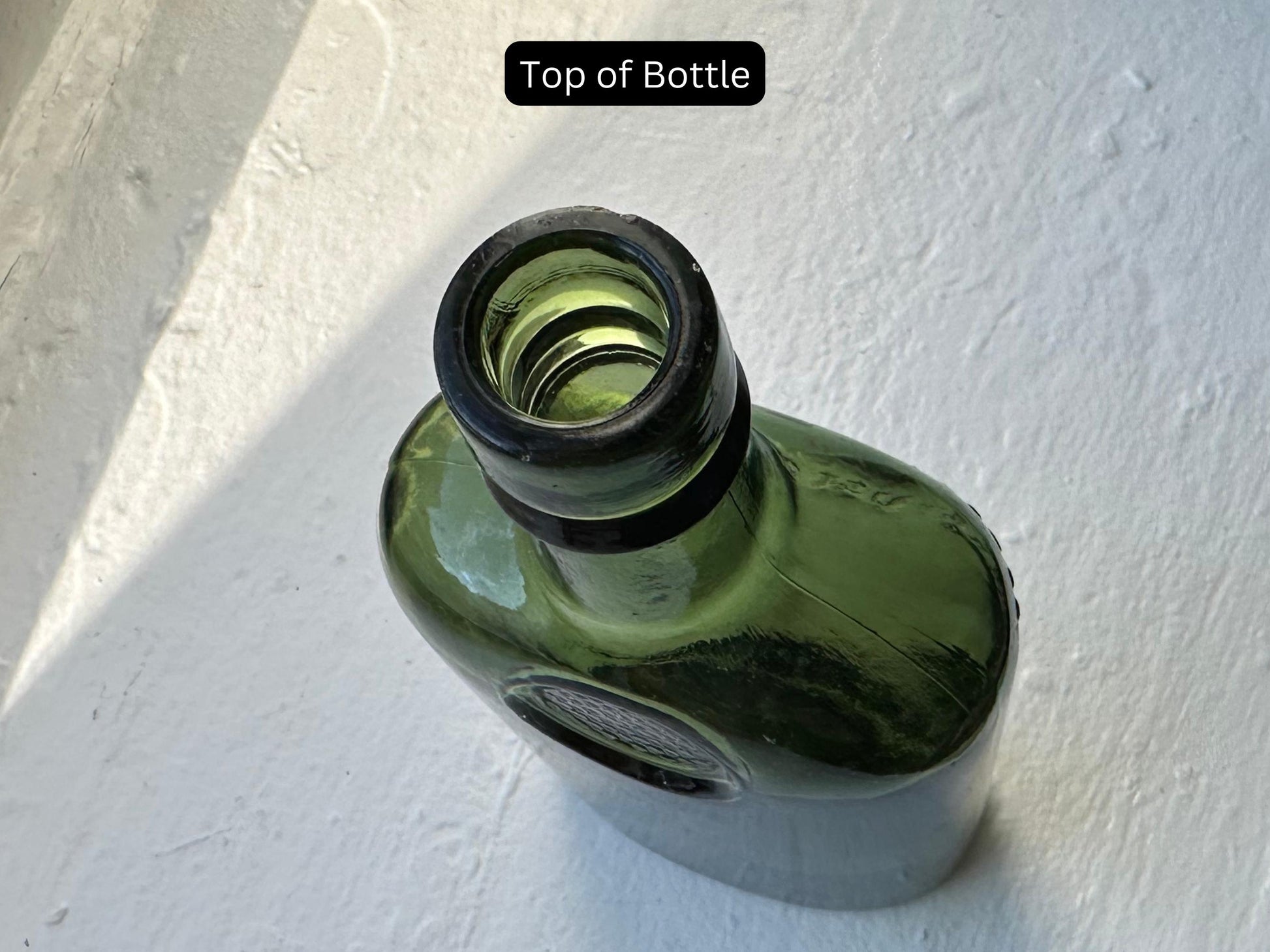 The top of a green glass whiskey bottle, showing the opening and the lip. The bottle has a unique shape and is in vintage condition, perfect for collectors or antique enthusiasts.