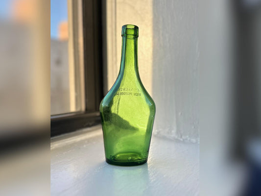 Close-up of the antique Italian wine bottle, highlighting its rich green hue and Veronese origins.
