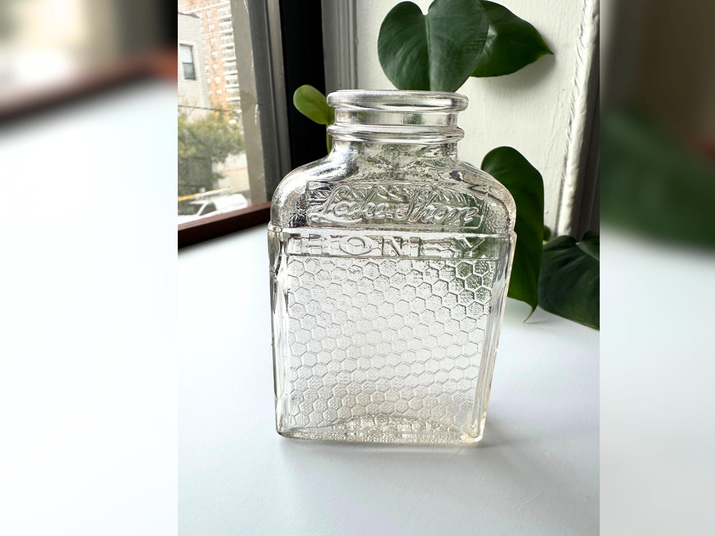 Side profile of a Lake Shore Honey jar standing upright, showing its narrow depth and tall rectangular silhouette. The honeycomb glass texture wraps from front to back, and light reflects off its edges, emphasizing the slight pink tint. Perfect for stylists or vintage collectors looking for versatile display pieces that bring sustainable, mid-century charm to fall and holiday decor.