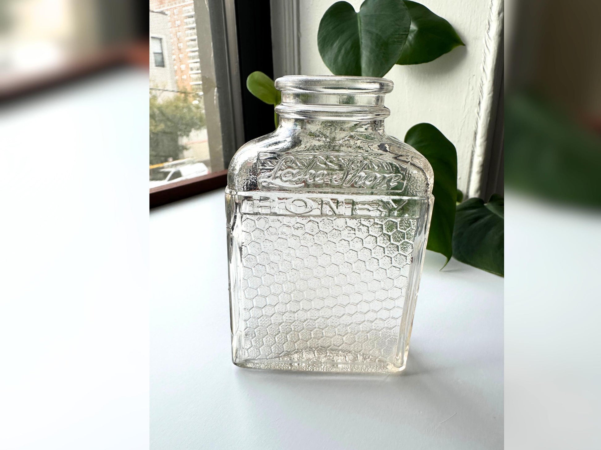 Side profile of a Lake Shore Honey jar standing upright, showing its narrow depth and tall rectangular silhouette. The honeycomb glass texture wraps from front to back, and light reflects off its edges, emphasizing the slight pink tint. Perfect for stylists or vintage collectors looking for versatile display pieces that bring sustainable, mid-century charm to fall and holiday decor.