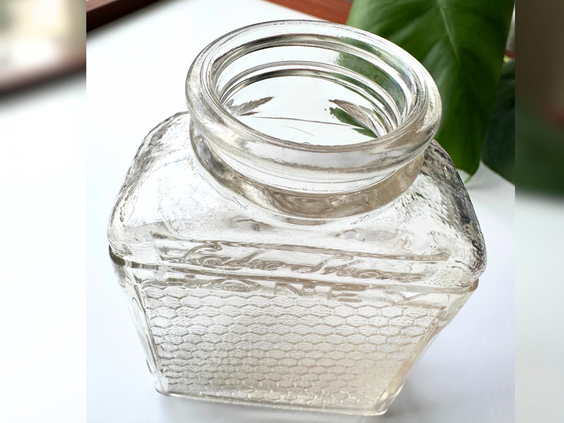 A close-up photo of the vintage Lake Shore Honeycomb jar viewed from above, showing the wide round mouth and threaded rim of the bottle. The clear glass has a subtle pink tint and displays the embossed "Lake Shore HONEY" lettering on the shoulder. This overhead view highlights the jar’s thick glass and square shoulders, ideal for sustainable storage, display, or reuse in eco-friendly home decor or vintage kitchen vignettes.