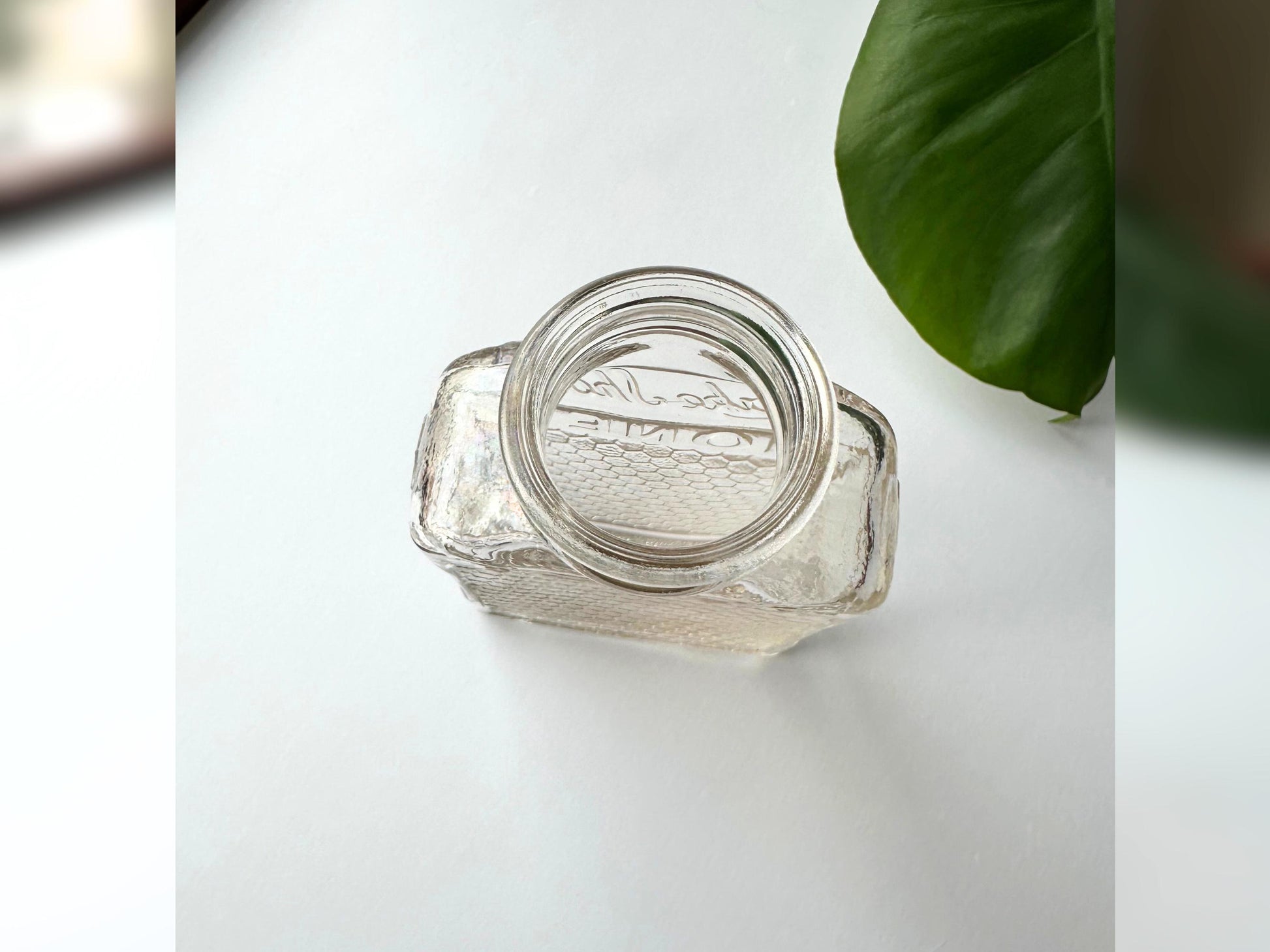 Top-down view of a vintage Lake Shore Honey jar, showcasing its wide round mouth and thick glass lip. The honeycomb texture wraps around the body, and the subtle pinkish tint of the glass catches soft light. This perspective highlights its reuse potential as a small vase or candleholder. Ideal for eco-conscious home styling, apothecary aesthetics, or vintage fall decor that celebrates texture, light, and sustainable materials.