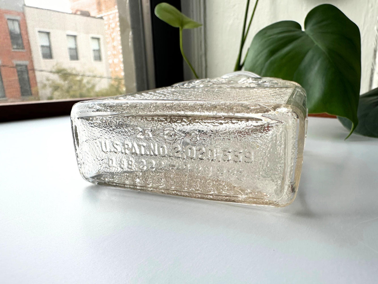 Underside view of a Lake Shore Honey jar showing embossed U.S. Patent Nos. D89222 and 2030559, confirming its 1930s–1950s origin. The glass base shows wear consistent with age, and the rectangular footprint reveals its apothecary-style design. A key reference for vintage collectors and sustainable home decorators looking to add authentic, repurposed glassware to fall vignettes or rustic shelves.