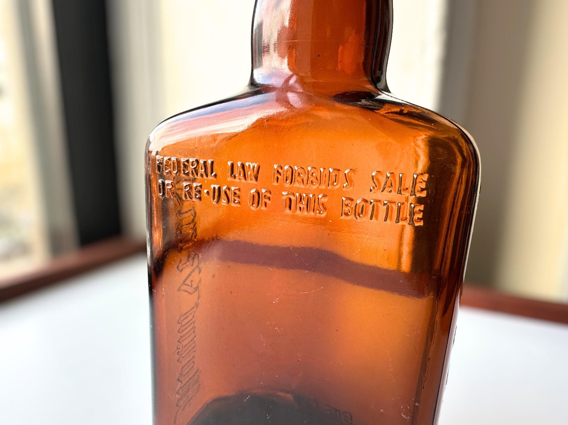 Vintage Mount Vernon straight whiskey bottle, 8.5 inches tall by 3.5 inches wide, rescued from NYC beaches. Features embossed "MOUNT VERNON" lettering and "FEDERAL LAW FORBIDS SALE OR REUSE OF THIS BOTTLE" text authentic to mid-century American spirits bottles. Base marked "ONE PINT" for capacity. Perfect for farmhouse decor, vintage bar cart styling, cottagecore displays, or as unique bud vase. Authentic dug bottle with age-appropriate patina from Brooklyn Sea Glass.