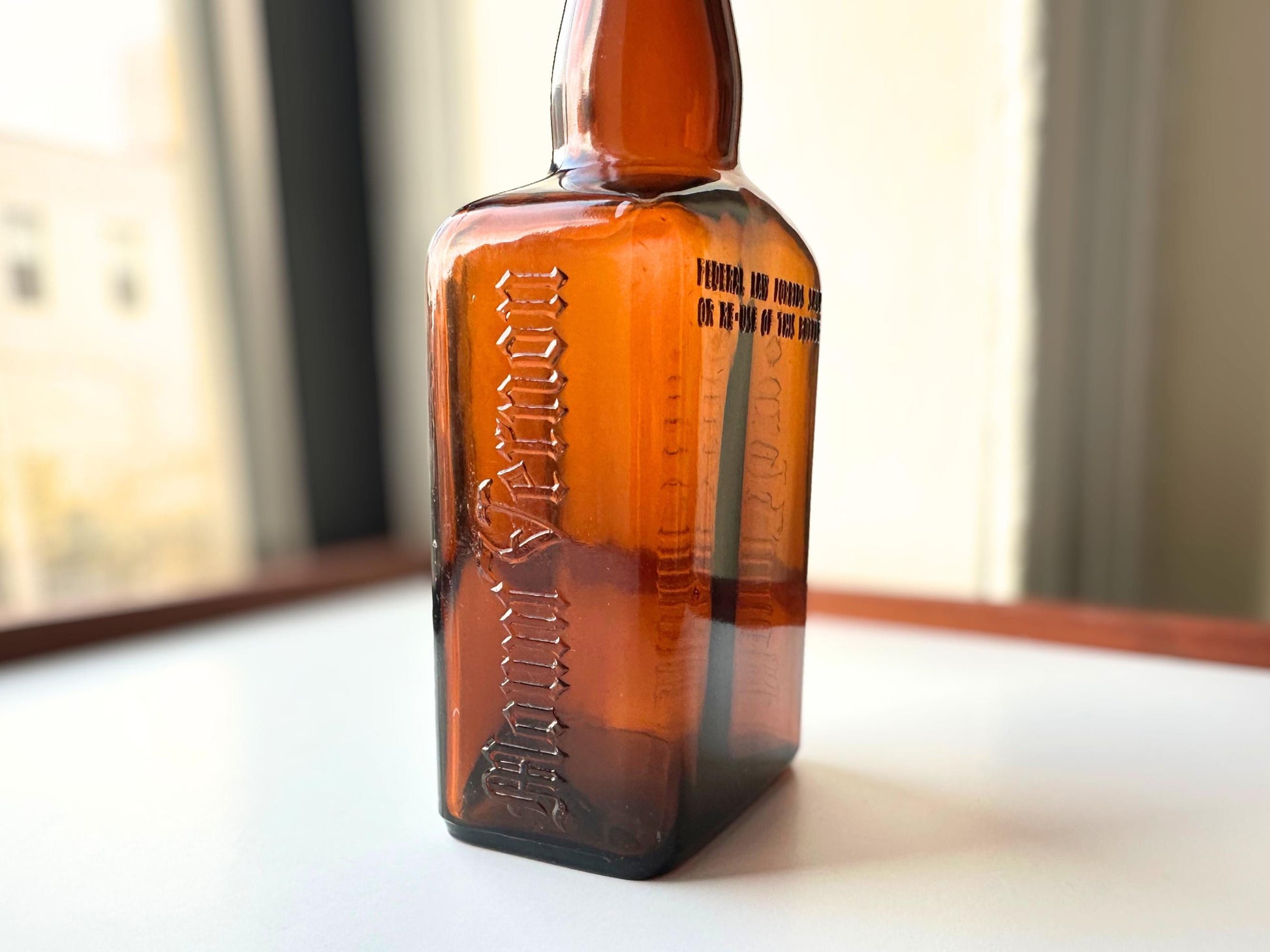 Vintage Mount Vernon straight whiskey bottle, 8.5 inches tall by 3.5 inches wide, rescued from NYC beaches. Features embossed "MOUNT VERNON" lettering and "FEDERAL LAW FORBIDS SALE OR REUSE OF THIS BOTTLE" text authentic to mid-century American spirits bottles. Base marked "ONE PINT" for capacity. Perfect for farmhouse decor, vintage bar cart styling, cottagecore displays, or as unique bud vase. Authentic dug bottle with age-appropriate patina from Brooklyn Sea Glass.