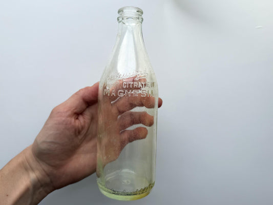 Vintage glass bottle with Citrate of Magnesia label, likely used for a health tonic. Clear glass with a slightly tapered shape.