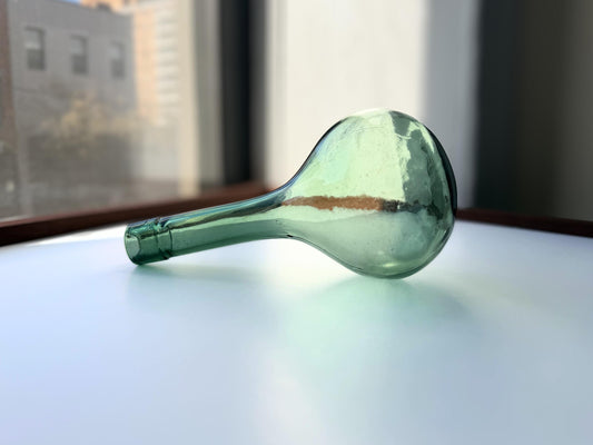 Vintage sage green round-bottom wine bottle lying on its side showing full length and classic teardrop silhouette with measurement scale