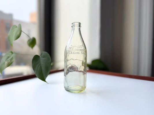 Vintage glass bottle with Citrate of Magnesia label, likely used for a health tonic. Clear glass with a slightly tapered shape.