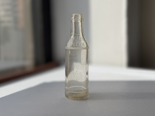 Manhattan Special espresso soda bottle angled left view, clear embossed glass, Brooklyn NYC since 1895
