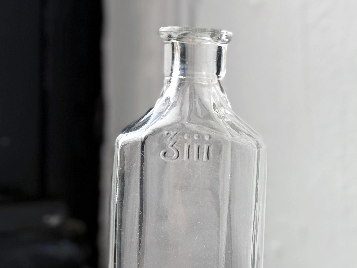 Owens Glass medicine bottle 3iii embossing close-up on clear glass, early American pharmaceutical bottle