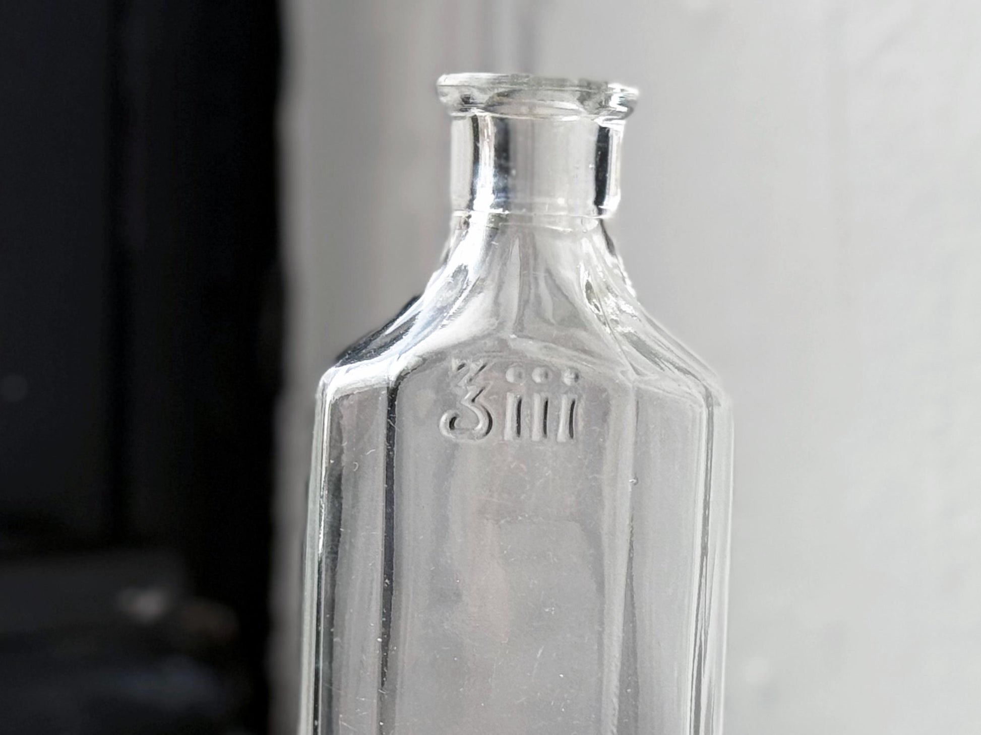 Owens Glass medicine bottle 3iii embossing close-up on clear glass, early American pharmaceutical bottle