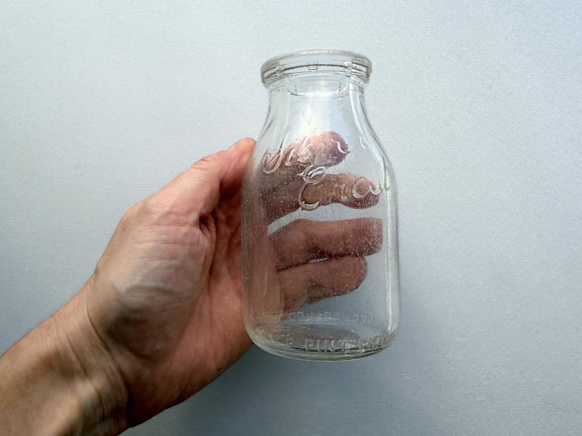 Hand holding Silver Crest Dairy milk bottle showing embossed dairy name detail