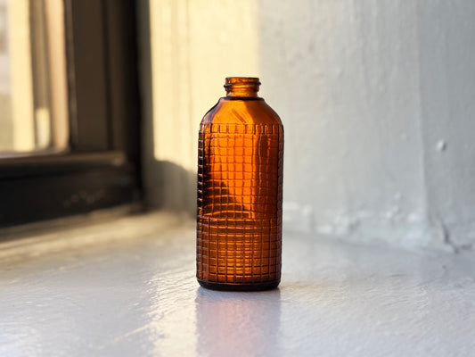 Vintage amber waffle grid bottle full front view, raised geometric texture 4.25 inches tall NYC recovery