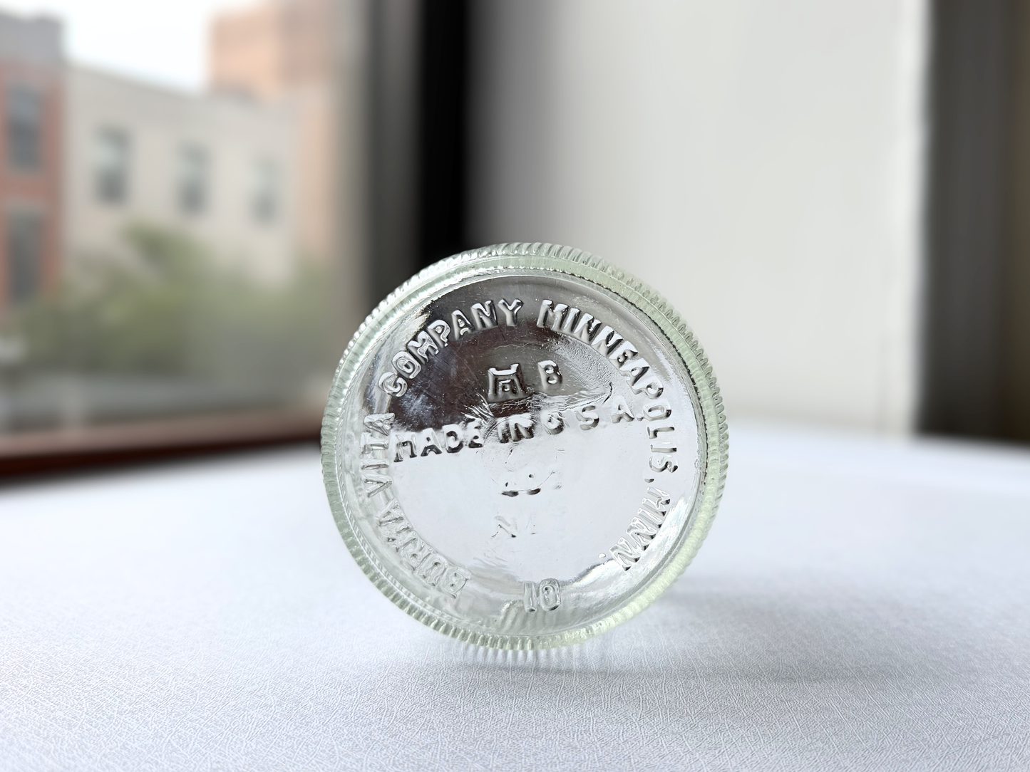 Close-up of the embossed base of a vintage Burma-Shave jar reading Burma Vita Company Minneapolis Minn Made in USA, confirming its mid-century American origin.