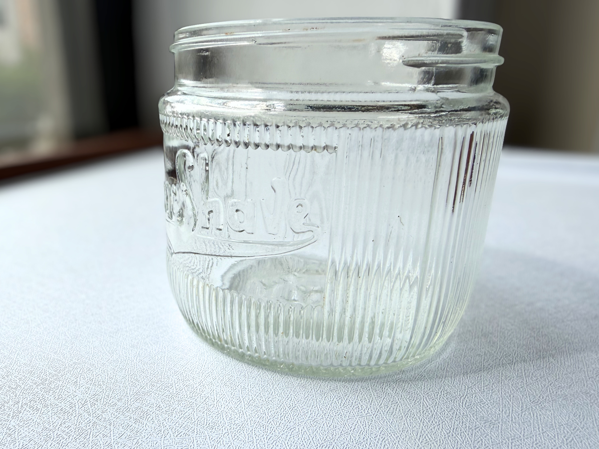 Full length view of a vintage ribbed glass Burma-Shave jar standing upright, showing its compact, textured silhouette.
